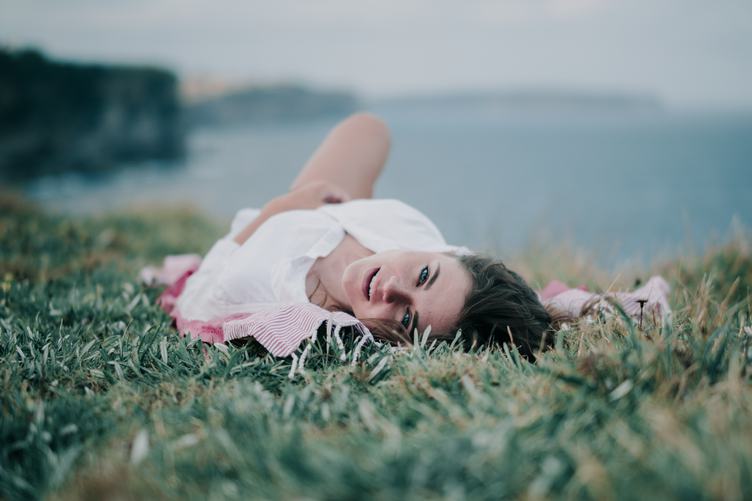 Joyful Young Woman Lies on the Grass