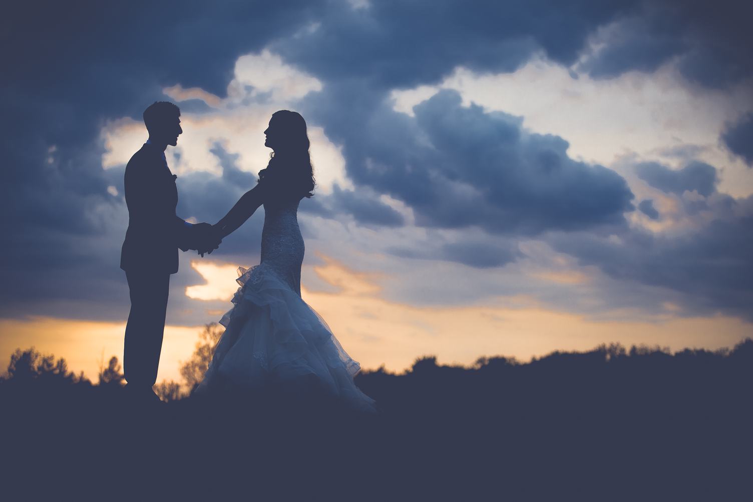 Wedding Couple on the Hill Holding Hands at Sunset
