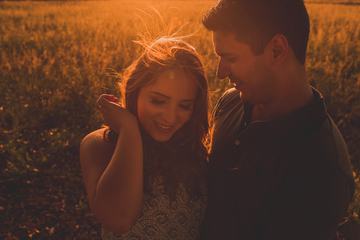 Happy Couple Standing in the Field at the Sunset